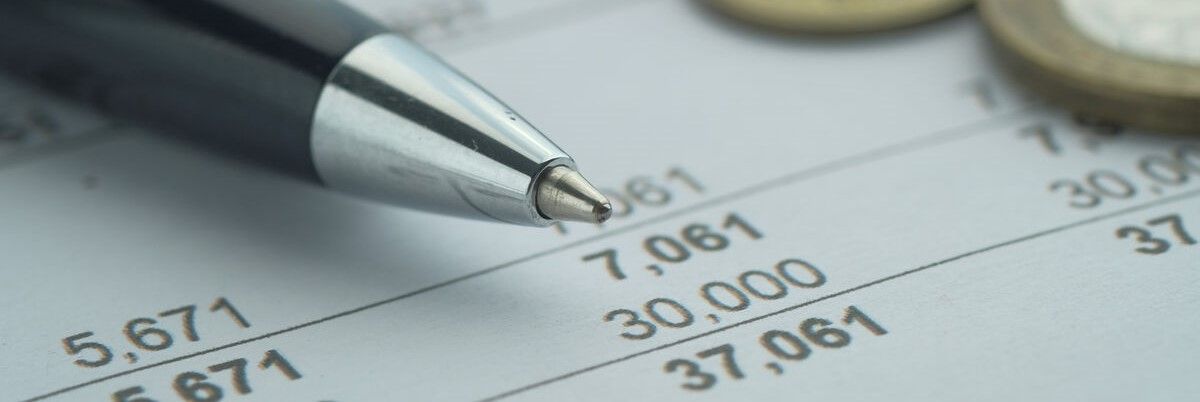 Ballpoint pen with written budget and pound coins