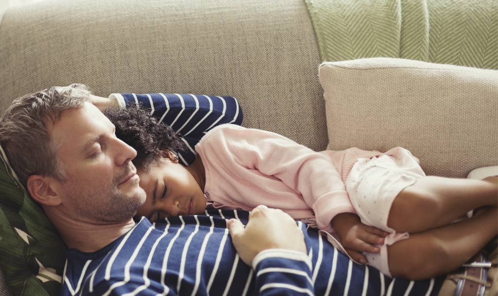 A man holding a baby on the sofa