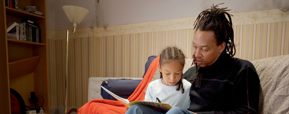 A man reads a story to a child sitting on his lap