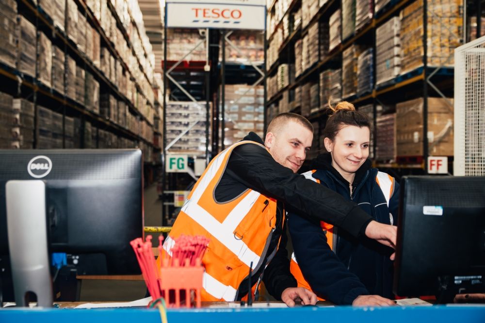 Tesco workers viewing computer at distribution centre