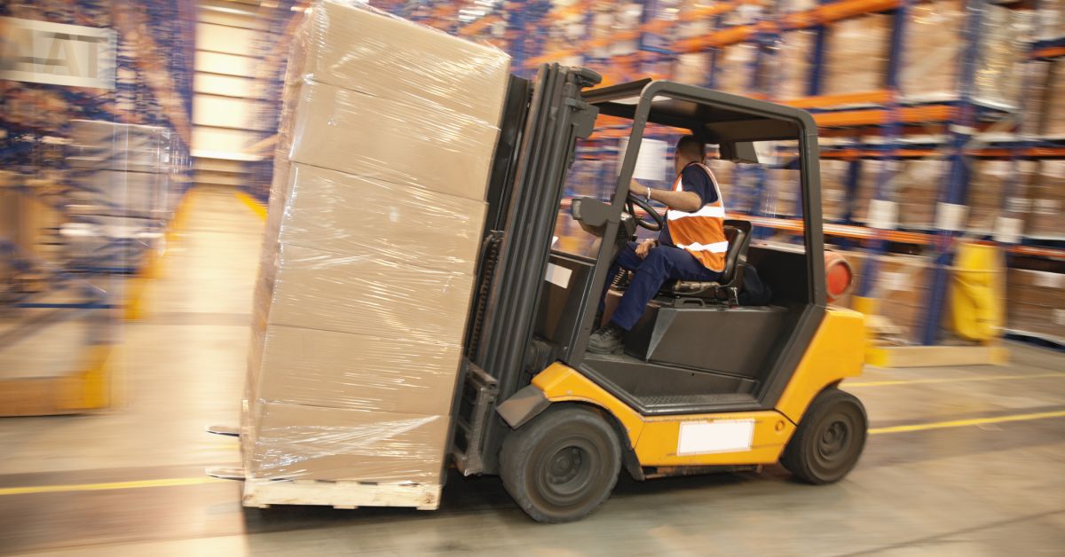 Man reverses forklift truck in a warehouse