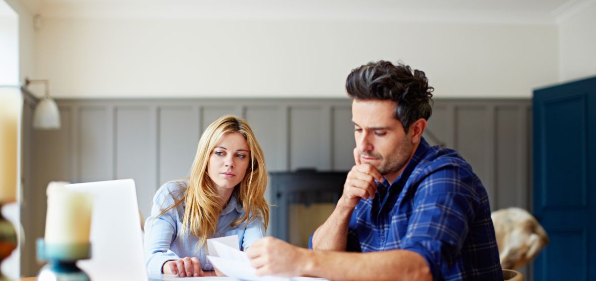a worried couple stare at a comupter screen