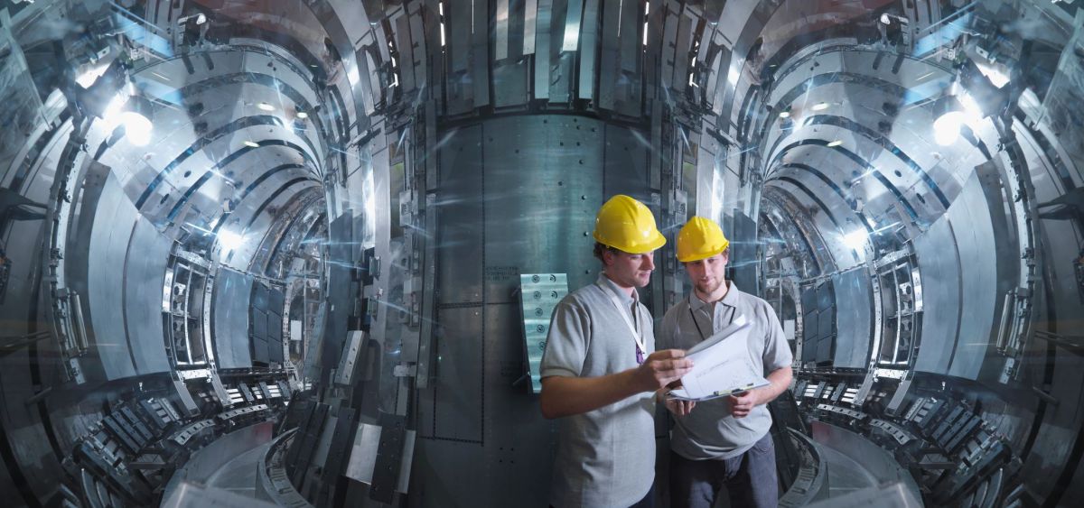 two workers in hard hats consult a chart in a nuclear reactor