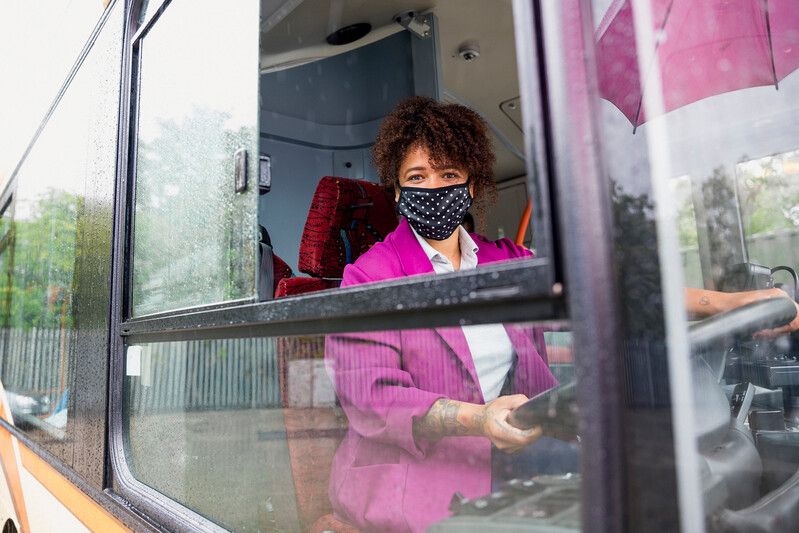 Woman bus driver wearing face mask behind the wheel