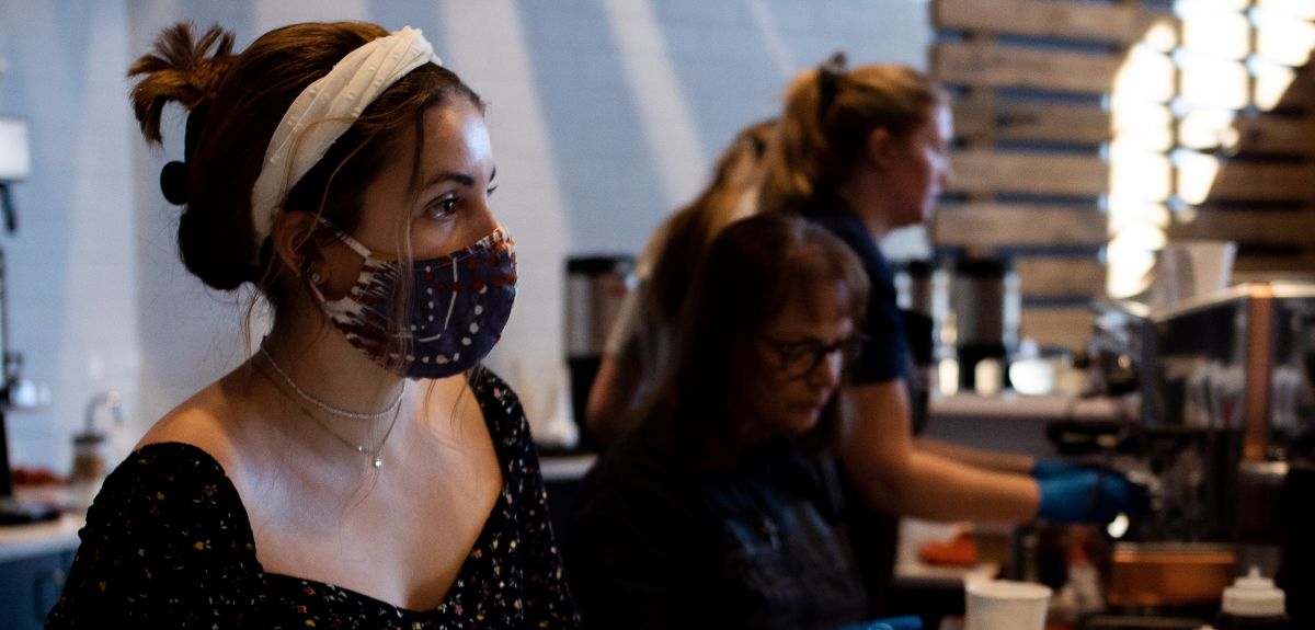 Woman in a mask serving in a cafe 