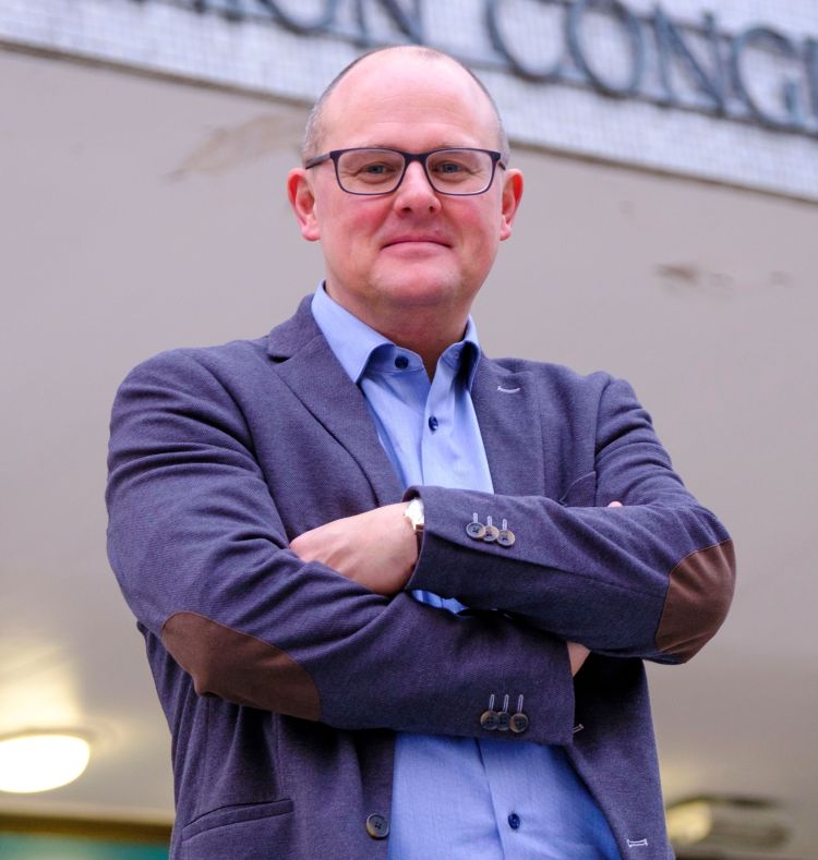 Paul Nowak standing with crossed arms and smiling
