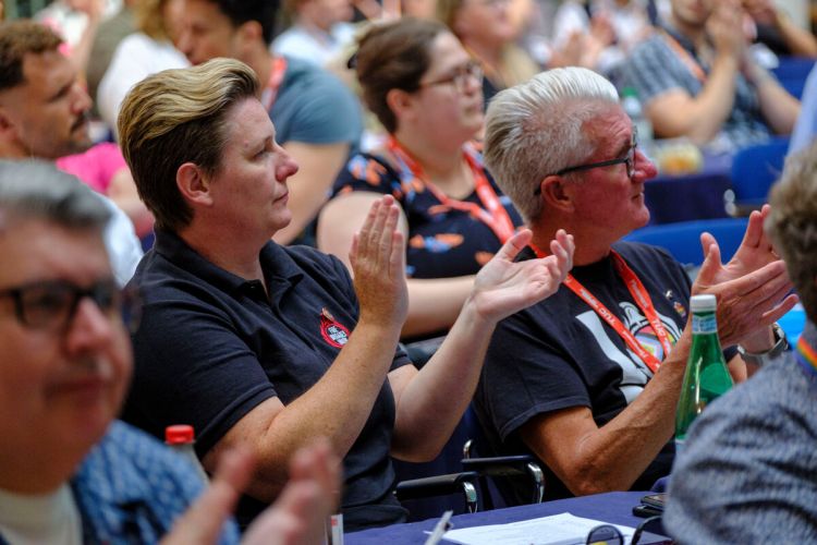 Two delegates clapping in a crowd