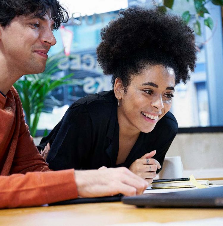 A woman and man looking happily at a laptop screen