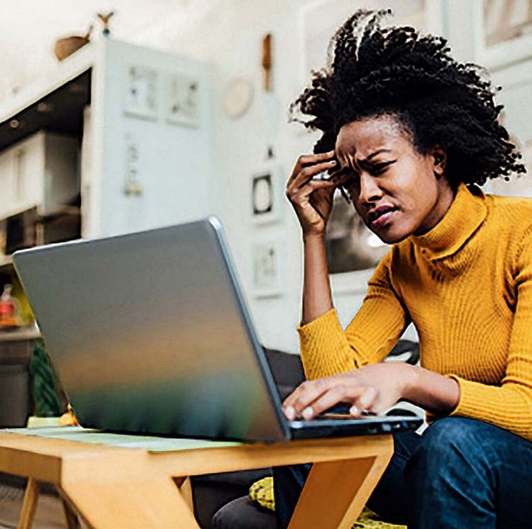 Woman sitting lopping frustrated at her laptop screen