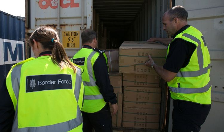 Border force workers unload boxes from the back of a lorry