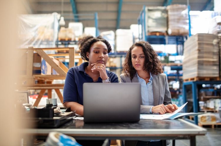 Two women looking together at a shared laptop at work