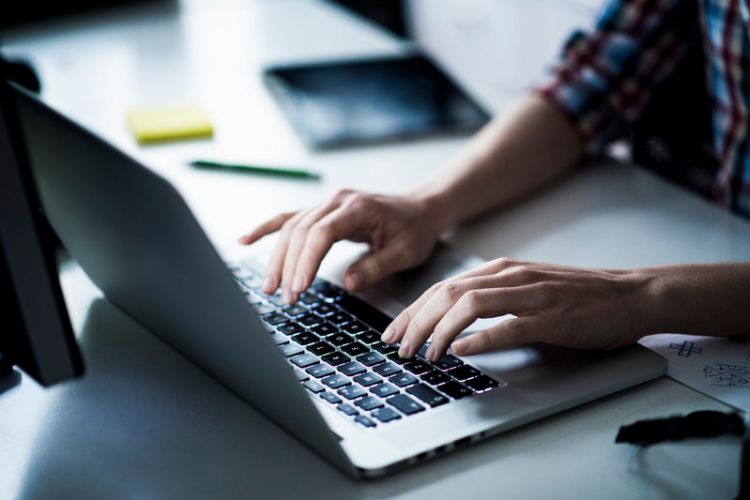 A picture of someone typing on a laptop