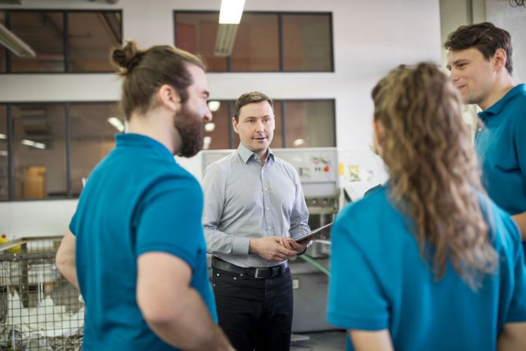 A team of four workers standing and talking together face to face