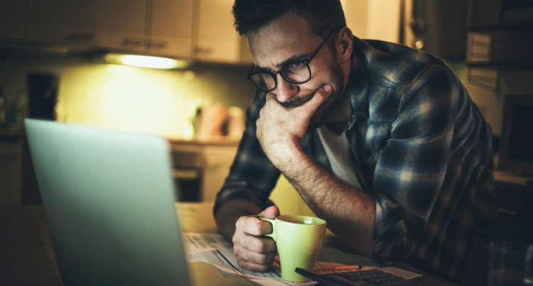 A worried-looking man stares at a computer screen