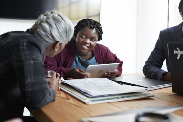 Young disabled entrepreneur discussing with coworker while in board meeting at workplace