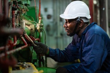 A ship maintenance worker is maintaining the ship's engine room