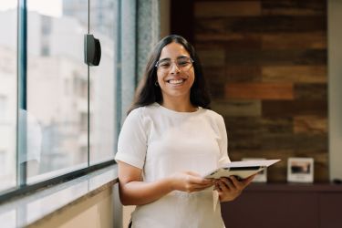 Female intern standing confidently with digital device