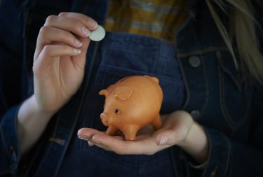 person putting money into a piggy bank