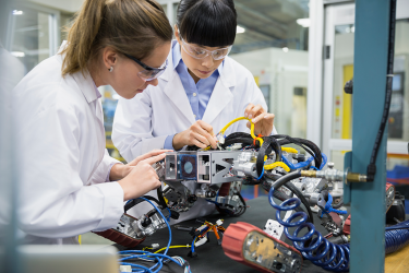 Two workers examine a robot