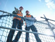 Two builders on scaffolding with blue sky behind them