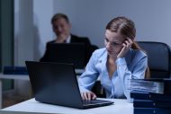 Professional woman on laptop looking stressed with man in the background