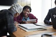 Young disabled entrepreneur discussing with coworker while in board meeting at workplace