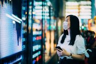 Businesswoman with protective face mask checking financial trading data on smartphone