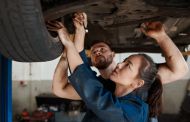 Shot of two mechanics working together under a lifted car