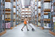 Worker pushing hand truck in warehouse