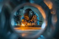 Industrial Worker Welding Metal with Sparks in Factory Production Line - stock photo