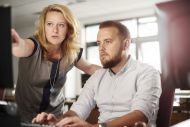 Female teacher chats to a male adult students in a computer lab