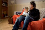 A man reads a story to a child sitting on his lap