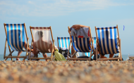 Four people relaxing on the beach on deckchairs