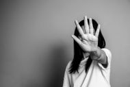 Black and white image of a woman with her hand up covering her face