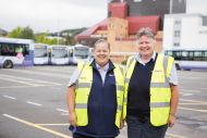 Two people in hi-vis jackets stand in a car park 