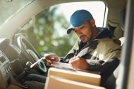 Delivery man reading addresses while sitting in a delivery van
