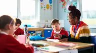 Primary school teacher helping boy with his school work 