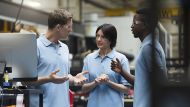 Three factory workers talking in front of a computer screen