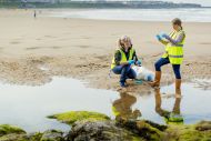 Two women outdoor workers gathering water samples from a beach