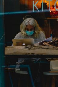 Woman reading in mask in cafe