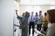 A group of workers standing and taking notes 