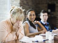 Woman worker sneezing next to colleagues at work
