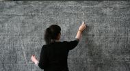 A teacher writes on a blackboard