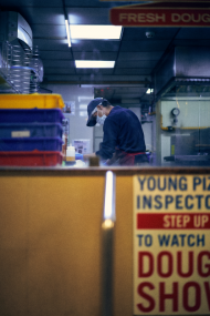 man working in mask at pizza cafe